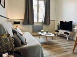 ein Wohnzimmer mit einem Sofa und einem TV in der Unterkunft Le Nid Vert, T2 cocooning à Rennes, proche gare in Rennes