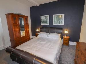 a bedroom with a large bed with a leather headboard at The Old Sorting Office in Hawarden