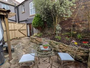 un patio con mesa, sillas y una valla en The Old Sorting Office, en Hawarden