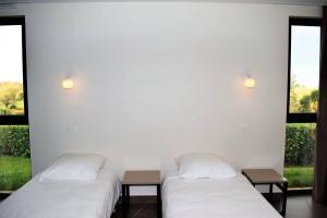 2 Betten in einem Zimmer mit 2 Fenstern in der Unterkunft Maison neuve de plain-pied avec WIFI classée 3 étoiles à Trégastel Ref 466 in Trégastel