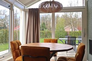 uma sala de jantar com mesa e cadeiras e uma grande janela em Vakantiewoning de Oeverzwaluw in hartje Drenthe em Zwiggelte