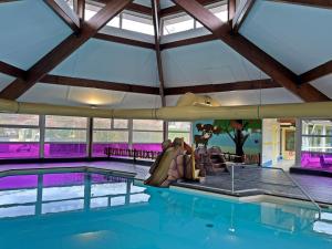 a large indoor swimming pool with a large glass ceiling at Vakantiewoning de Oeverzwaluw in hartje Drenthe in Zwiggelte