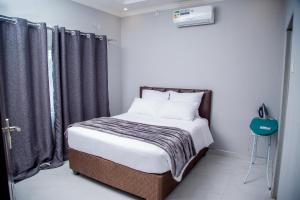 a small bedroom with a bed with black curtains at Modern Village Apartments in Chipata