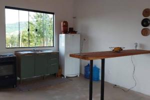 cocina con nevera, mesa y ventana en Sítio Âmbar - Família, tranquilidade e privacidade, en Lambari