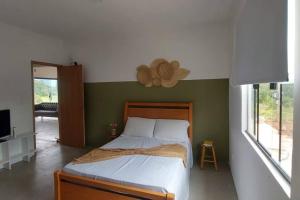 um quarto com uma cama e uma grande janela em Sítio Âmbar - Família, tranquilidade e privacidade em Lambari