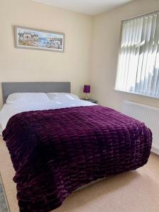 a bedroom with a purple blanket on a bed at Eden Stay in Morecambe