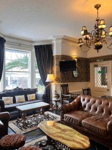 uma sala de estar com um sofá e uma mesa em Rose Tor Hotel em Llandudno