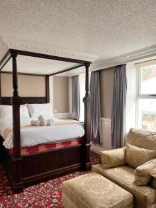 sypialnia z łóżkiem z baldachimem i kanapą w obiekcie Rose Tor Hotel w mieście Llandudno