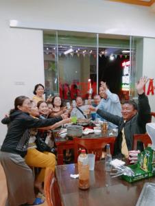 grupa ludzi siedzących przy stole z rękami w górze w obiekcie Hien Thuc Hotel w mieście Ninh Binh