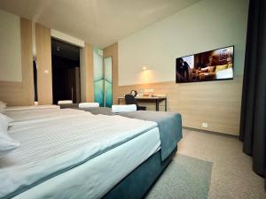 a hotel room with two beds and a tv on the wall at Hotel Turkus in Białystok