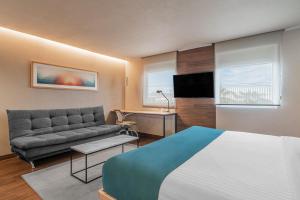 um quarto de hotel com uma cama e um sofá em City Express Suites by Marriott Queretaro em Querétaro