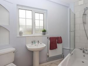 a white bathroom with a sink and a toilet and a tub at Glebe Cottage in Yelverton