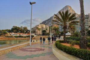 a group of people walking down a sidewalk with a mountain in the background at Calpe apartamento nuevo primera línea playa y piscina wifi in Calpe