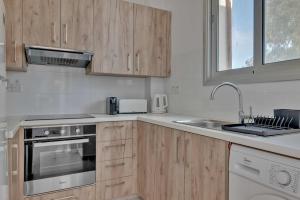 a kitchen with wooden cabinets and a sink at Phaedrus Living: City Center Residences Emerald in Nicosia