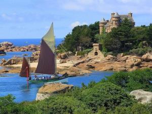 un velero en un río con un castillo en el fondo en Maisonnette de charme à 400m de la plage à TREGASTEL - Réf 64, en Trégastel