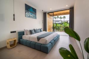 a bedroom with a large bed with a blue couch at Sunny Village Berawa in Canggu