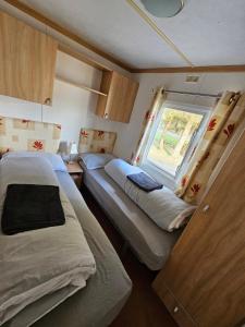 a small room with two beds and a window at Honey Cottage Caravan Park in Selkirk