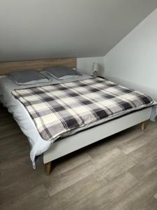 ein Bett mit einer karierten Decke auf einem Zimmer in der Unterkunft Gites aux deux Hameaux 2 in Saint-Pierre-Bois