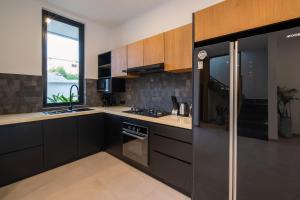 a kitchen with black cabinets and a stove top oven at Sunny Village Berawa in Canggu