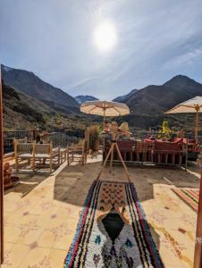 a patio with tables and umbrellas with mountains in the background at Riad Dar Omar in Imlil