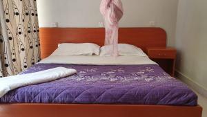 a bed with a purple comforter and a wooden headboard at Arise Africa International Christian Guesthouse in Jinja