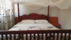 1 dormitorio con cama de madera y dosel en Arise Africa International Christian Guesthouse, en Jinja