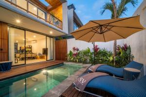 an indoor swimming pool with an umbrella next to a house at Sunny Village Berawa in Canggu