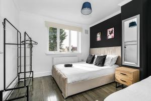 Luxury Large House With Games Room Sleeps Up to 12 في Feltham: غرفة نوم مع سرير وبجدار لكنة سوداء