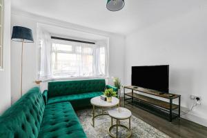 a living room with a green couch and a television at Luxury Large House With Games Room Sleeps Up to 12 in Feltham
