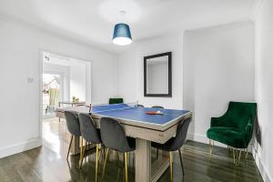 Luxury Large House With Games Room Sleeps Up to 12 في Feltham: غرفة طعام مع طاولة تنس وكراسي