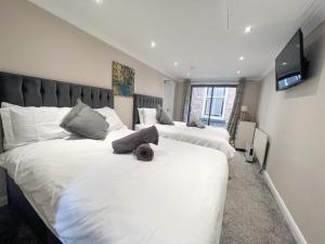 1 dormitorio con 2 camas con sábanas blancas y TV en Beldon House, en Brigg
