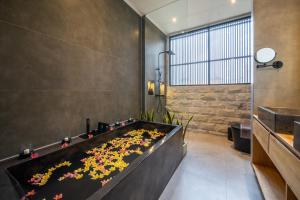 a large bathtub filled with flowers in a bathroom at Sunny Village Berawa in Canggu