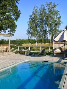 una piscina con 2 sillas y una sombrilla en Heritage-listed country cottages en Eskilstuna