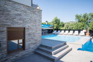 - une piscine dans un bâtiment en briques avec des chaises dans l'établissement Luxury Apartment & Rooms, à Ljubuški