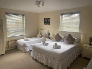 a bedroom with two beds and two windows at Runnymede Court Hotel in Saint Helier Jersey