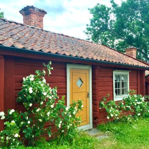 un piccolo cottage rosso con una porta gialla di Heritage-listed country cottages a Eskilstuna