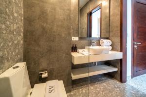 a bathroom with a sink and a toilet and a mirror at Sunny Village Berawa in Canggu