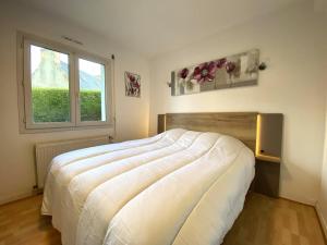 a bedroom with a large white bed with a window at Maison VUE MER, jardin, terrasse, WIFI, au SUD, à TREBEURDEN - Réf 663 in Trébeurden