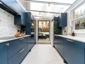 una cocina con armarios azules y una gran ventana en Stunning flat Richmond Bridge Pass The Keys, en Twickenham