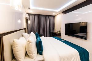 a bedroom with a white bed and a television at BON Hotel Nest Garki II Abuja in Abuja