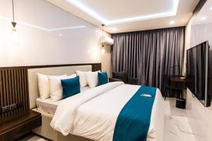 a bedroom with a large bed with blue pillows at BON Hotel Nest Garki II Abuja in Abuja