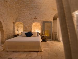 um quarto com uma cama numa parede de tijolos em Nina Trulli Resort em Selva di Fasano