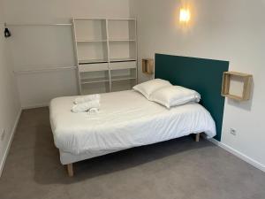 Schlafzimmer mit einem Bett mit weißer Bettwäsche und Kissen in der Unterkunft APPARTEMENT T3 hyper centre numéro 002 in Roanne