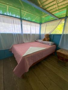 un osito de peluche sentado en una cama en una tienda en Amazon tucuxi, en Mazán
