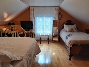 a bedroom with two beds and a television and a window at Gîte au Charme Victorien in Beauceville