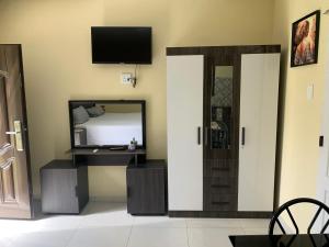 a room with a mirror and a tv on the wall at First derby Lodge in Benoni