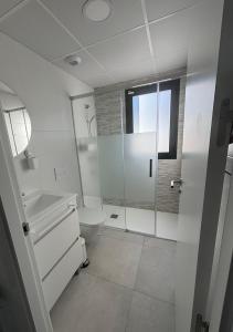 a white bathroom with a toilet and a window at Casa Blu Blu - Your Holidayhome with pool near the Beach! in Santiago de la Ribera