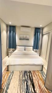 サラーラにあるHawana salalah Apartment Acaciaのベッドルーム(青いカーテン付きの白い大型ベッド1台付)