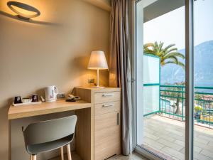 a room with a desk and a view of the ocean at Hotel Cristina in Limone sul Garda