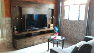 a living room with a television on a wooden entertainment center at CASA TEMPORADA PERUIBE in Peruíbe